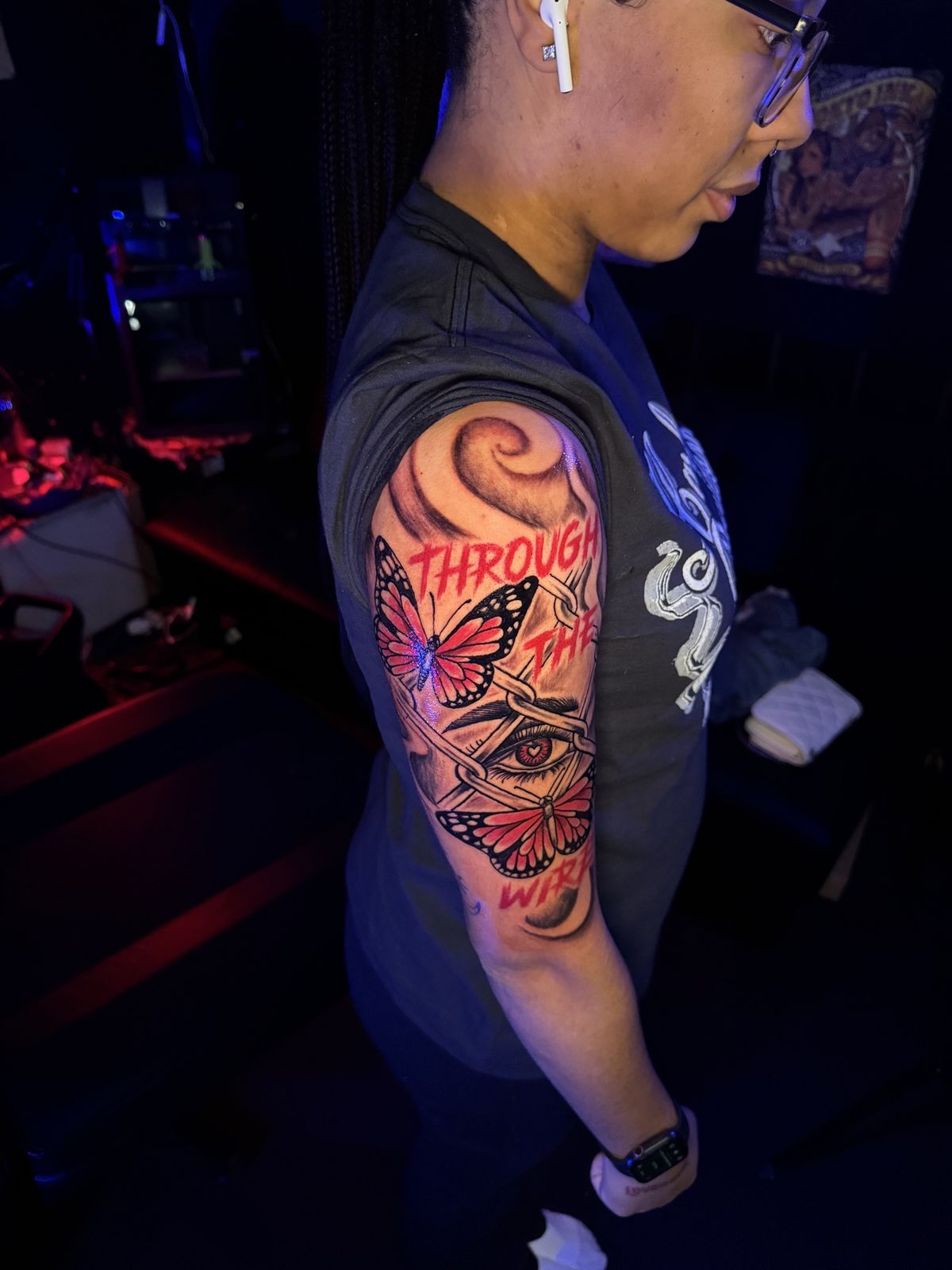 Through the wire: barbed wire eye with red butterflies, arm tattoo